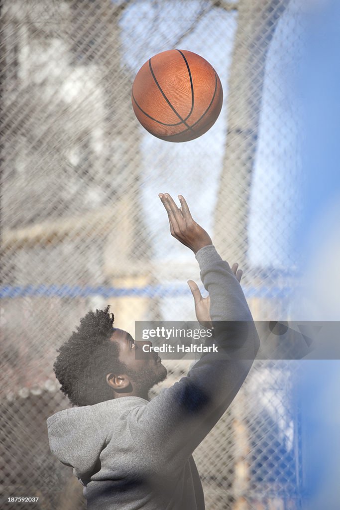 A hip young man playing basketball on a public outdoor court