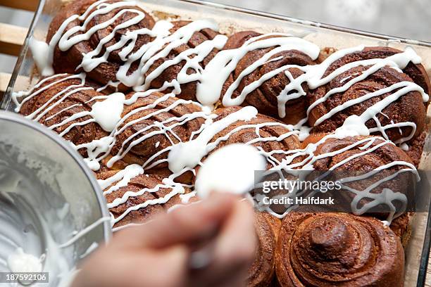 a coffee shop employee putting icing on a cinnamon rolls - berliner gebäck stock-fotos und bilder
