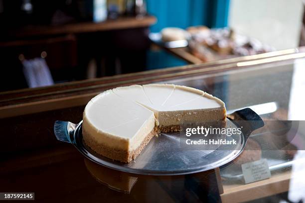 a cheesecake cut into slices on a display cabinet in a coffee shop - cheesecake fotografías e imágenes de stock