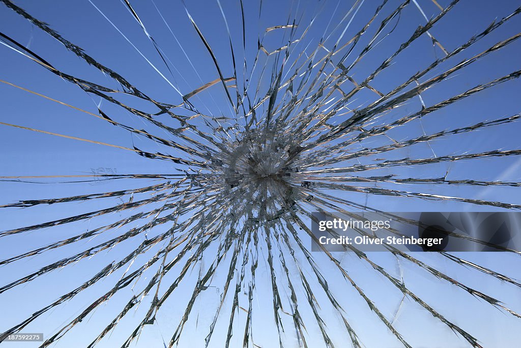 A clear blue sky seen through a shattered glass window