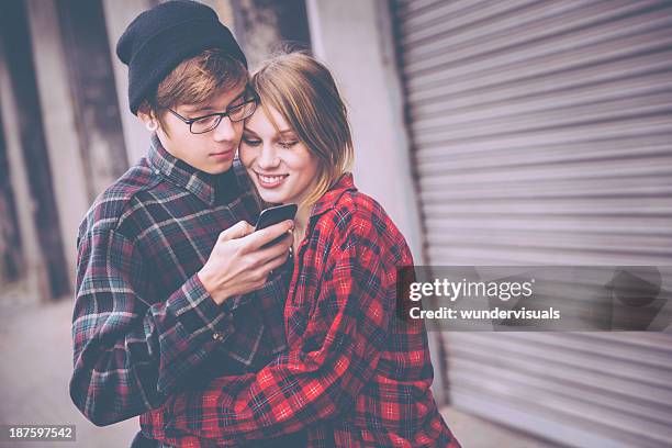 携帯電話を見ている 10 代のカップル - 波形鉄板 ストックフォトと画像
