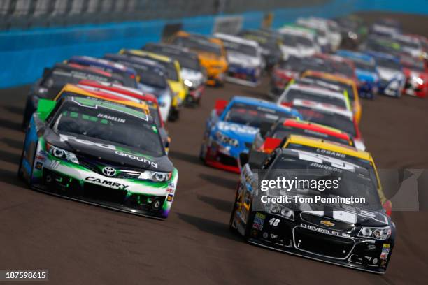 Jimmie Johnson, driver of the Lowe's/Kobalt Tools Chevrolet, and Denny Hamlin, driver of the FedEx Ground Toyota, lead the field during the NASCAR...