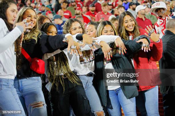 Members of the Oklahoma Sooners softball team hold up their World Series championship rings during a game against the West Virginia Mountaineers at...