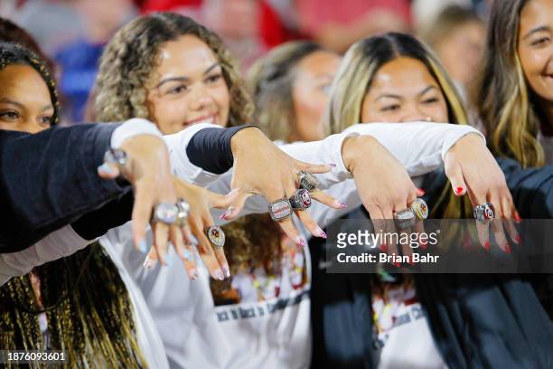 Members of the Oklahoma Sooners softball team hold up their World Series championship rings during a game against the West Virginia Mountaineers at...