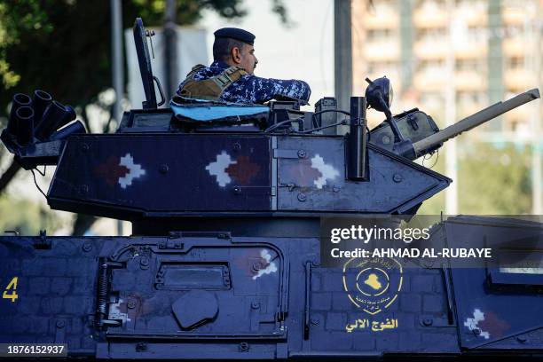 Member of the Iraqi security forces sits in the hatch of a turret of an armoured vehicle deployed along a street in Baghdad on December 26, 2023....