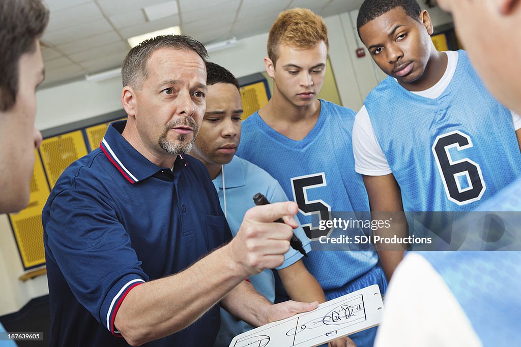 High school Treinador instruir os jogadores de basquetebol no Vestiário