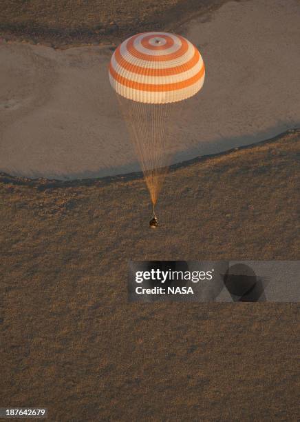 In this handout photo provided by NASA, The Soyuz TMA-09M capsule descends as it returns to Earth carrying the crew of Expedition 37 and the Sochi...