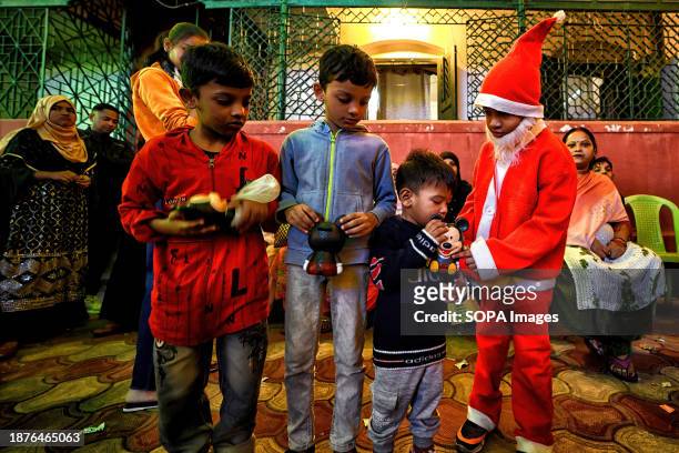 Little boy dressed as Santa seen distributing gifts to other children during the Christmas season.
