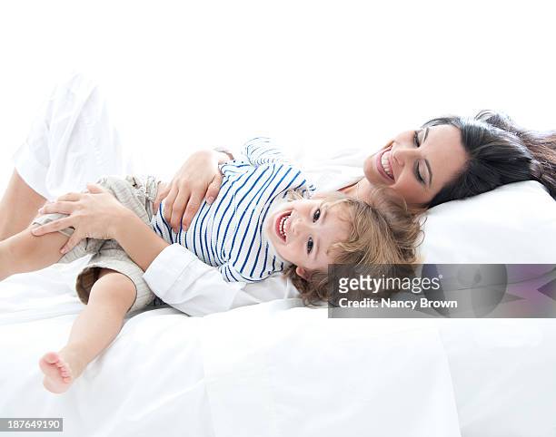 latin mom and son playing in bed. - bed on white stock pictures, royalty-free photos & images
