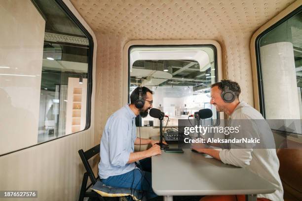 two hosts with headphones recording podcast in a soundproof broadcasting room - media equipment stock pictures, royalty-free photos & images