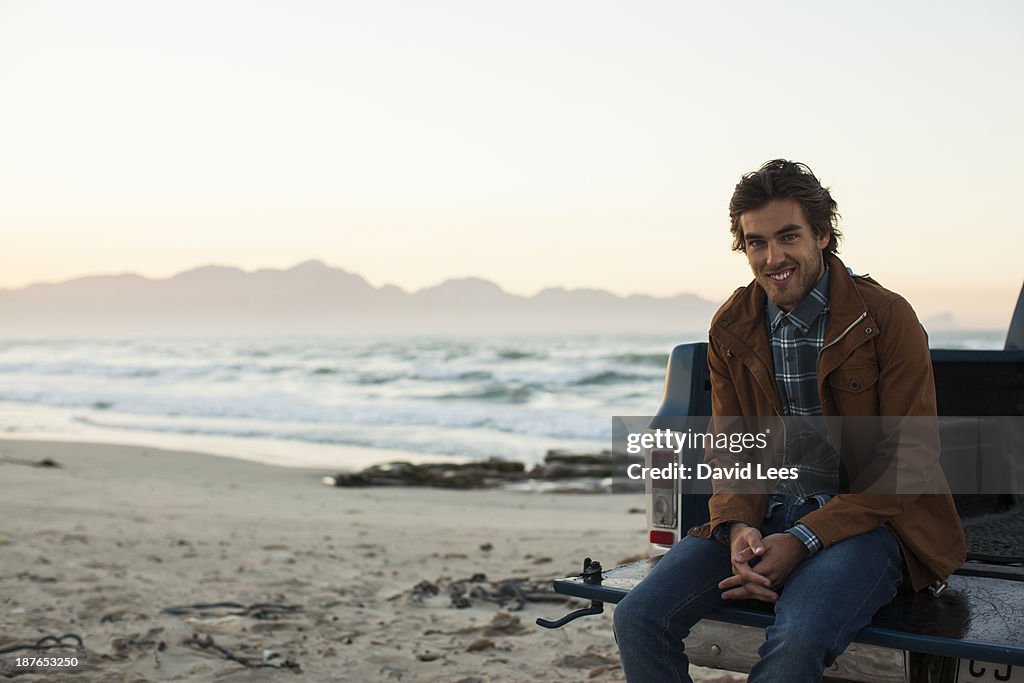 Man at beach sitting in back of truck