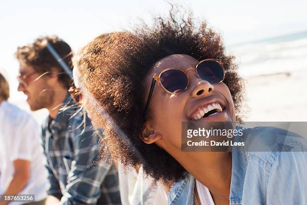 smiling friends at beach - frau mit sonnenbrille stock-fotos und bilder