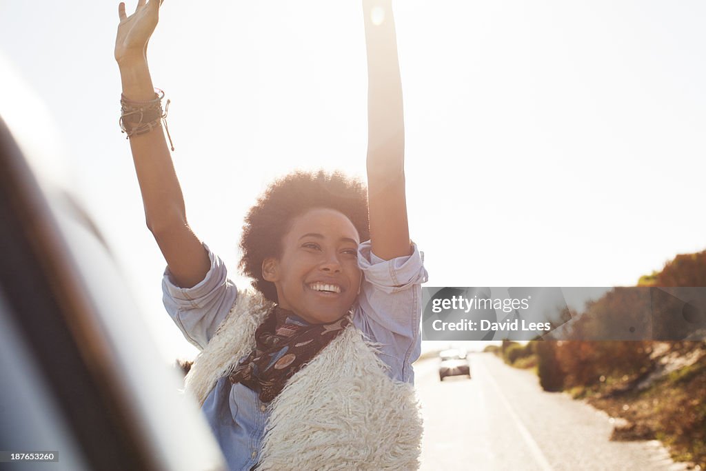 Smiling woman in back of truck with arms raised