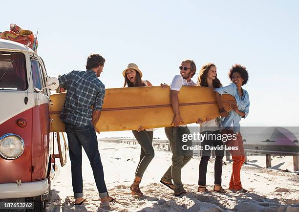 friends taking surfboard out of camper van - entladen stock-fotos und bilder