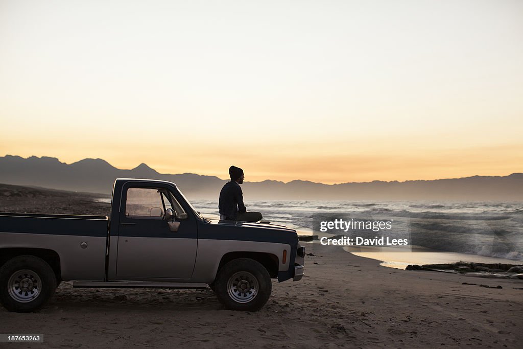 Man sitting on truck looking at ocean view