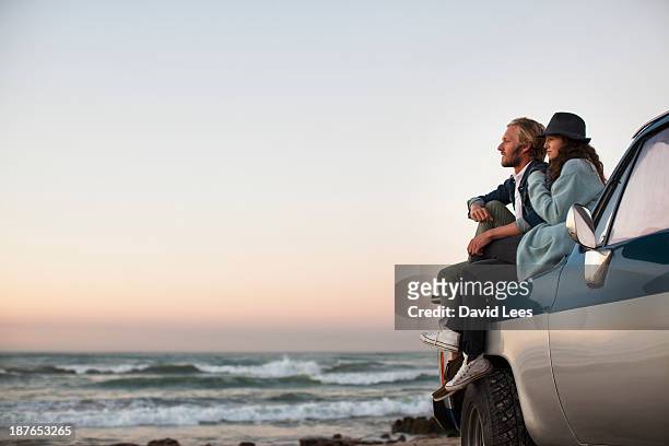 couple sitting on truck looking at ocean view - ドライブ旅行 ストックフォトと画像