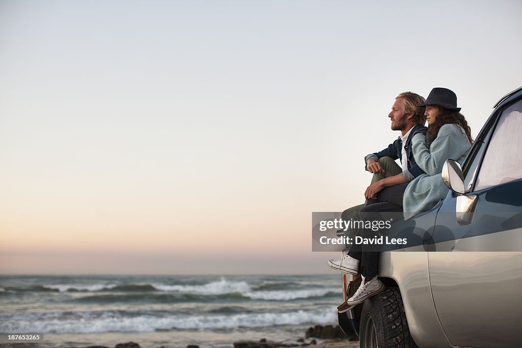 Couple sitting on truck looking at ocean view