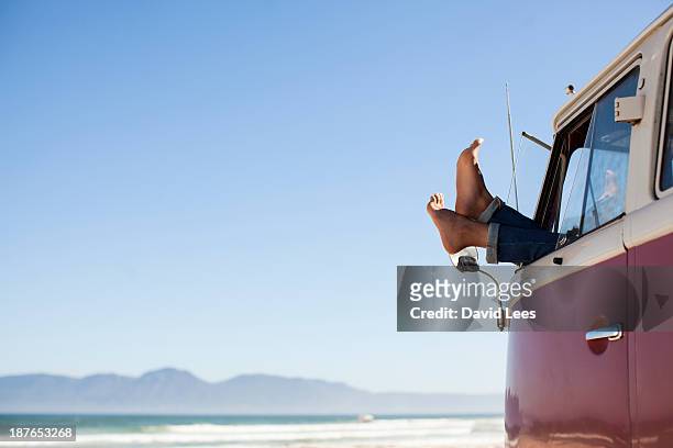 feet sticking out of camper van window at beach - attività del fine settimana foto e immagini stock