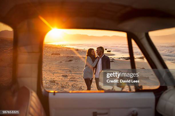 couple walking on beach by truck - couple on the beach with car stockfoto's en -beelden