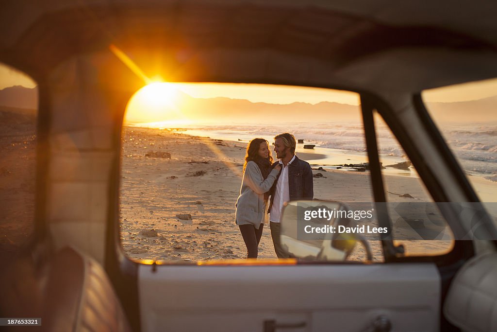 Couple walking on beach by truck