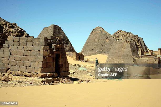 Visitor walks on November 10, 2013 past pyramids in the cemetary of Meroe north of Khartoum, Sudan. The Meroe dynasty, the last in a line of "black...