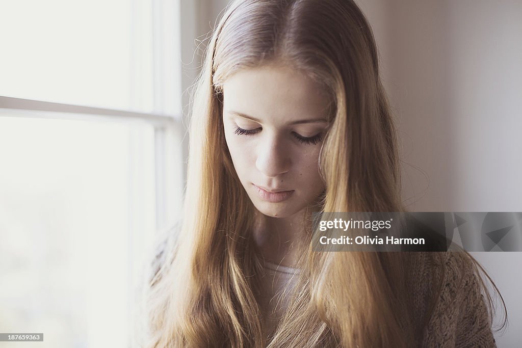 Portrait of a girl standing beside window