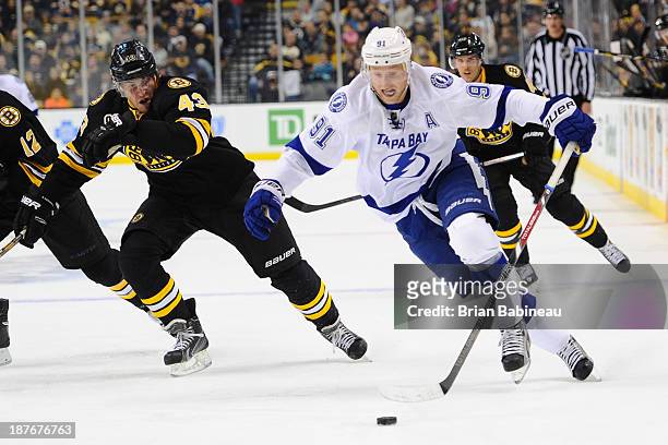 Steven Stamkos of the Tampa Bay Lightning skates with the puck against Matt Bartkowski of the Boston Bruins at the TD Garden on November 11, 2013 in...