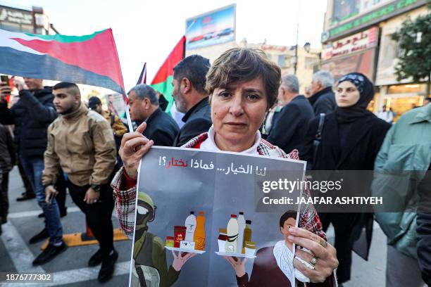 Woman holds a sign calling for the boycott of Israeli products during a demonstration in Ramallah in the occupied West Bank on December 26 as part of...