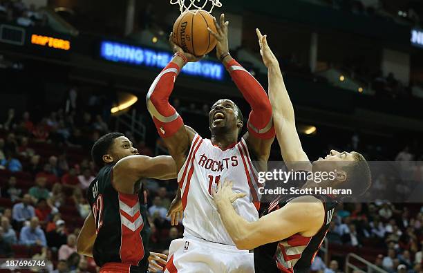 Dwight Howard of the Houston Rockets battles for the ball with Rudy Gay and Tyler Hansbrough of the Toronto Raptors at Toyota Center on November 11,...