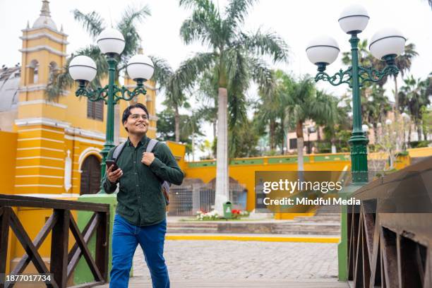 joven latino alegre disfrutando de las vistas en puente de los suspiros, iglesia la ermita, barranco, lima, perú - peruano fotografías e imágenes de stock