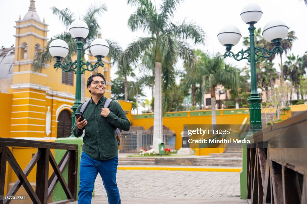 Joyeux jeune homme latin profitant des sites touristiques à Puente de los Suspiros, Iglesia la Ermita, Barranco, Lima, Pérou