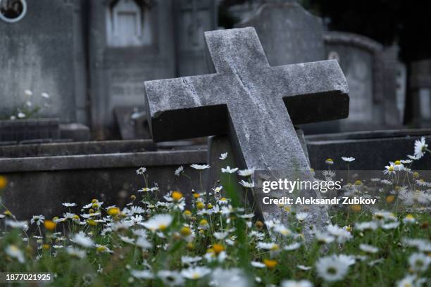 the city cemetery with old unkempt graves. stone tombstones, metal crosses. city cemetery. gravestones and stone crosses, abandoned and overgrown with grass graves of unknown people. the concept of death, the end of life, sadness, sorrow and loneliness. - grafsteen stockfoto's en -beelden