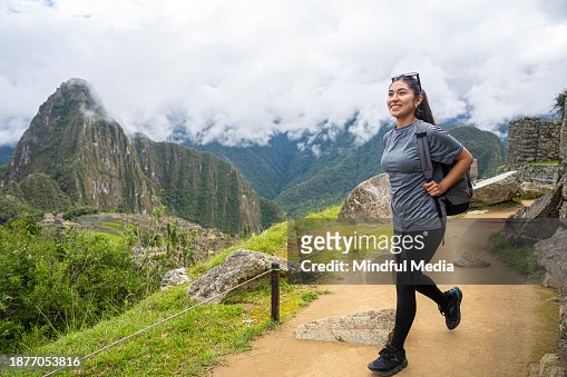 Young Latin female tourist walking on footpath in Sacred City of Machu Picchu, Peru