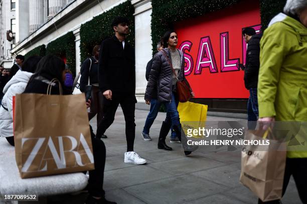 Shoppers carry their shopping bags along Oxford Street during the Boxing Day sales in London on December 26, 2023.