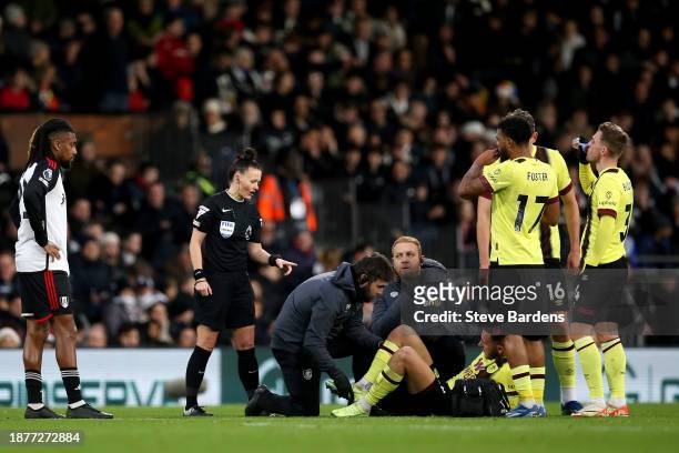 Referee Rebecca Welch stands over Josh Brownhill of Burnley as he receives medical treatment to an injury during the Premier League match between...
