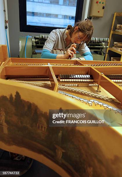 An employee of the Pleyel piano manufacturers works on a piano assembly line on December 3, 2010 in Saint-Denis, outside Paris. Once the favourite of...