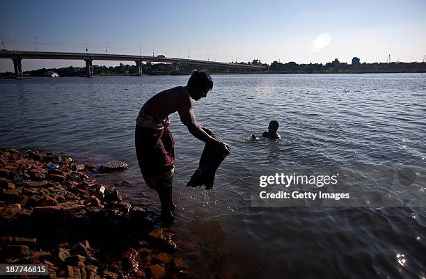 Barek washes a shirt while his friend Shajahan takes a bath in the Buriganga river, November 11, 2013 in the Hazaribagh neighborhood of Dhaka,...