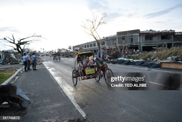 Residents riding on a tricycle cover their faces from the smell of cadavers along a road in Tacloban city, Leyte province central Philippines on...