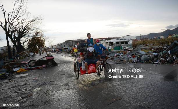 Residents ride on a tricycle as they pass through debris along a road in Tacloban city, Leyte province central Philippines on November 12 after super...