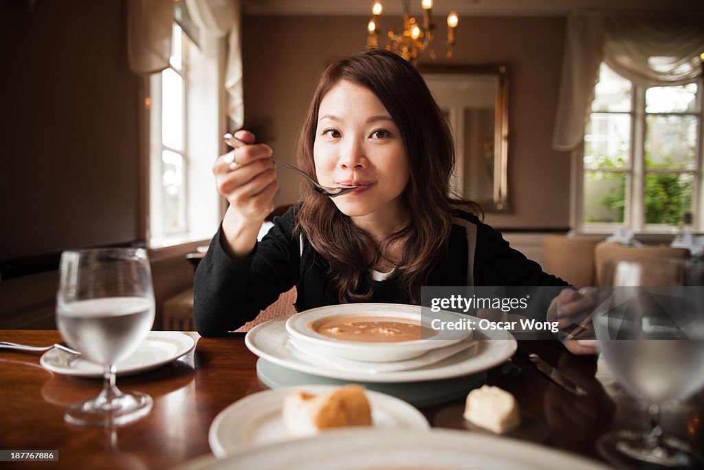 A youn girl is having soup in a posh restaurant