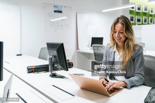 professional woman working on laptop in modern co-working space - gestor de proyectos fotografías e imágenes de stock