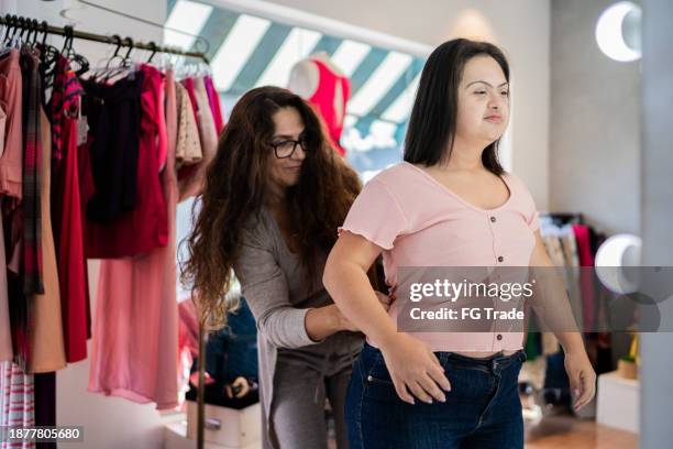 mother and daughter trying on clothes in a thrift store - down syndrome stock pictures, royalty-free photos & images