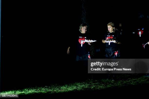 Two women carry plates during a charity dinner at Mirador de Cuatro Vientos, on 23 December, 2023 in Madrid, Spain. The solidarity initiative 'I...