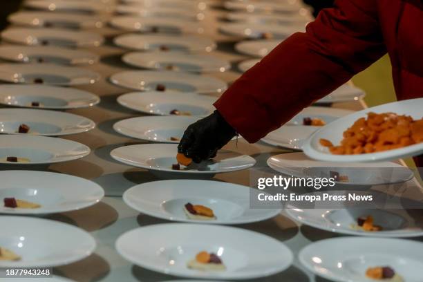 Person serves dishes during a charity dinner at the Mirador de Cuatro Vientos, on 23 December, 2023 in Madrid, Spain. The solidarity initiative 'I...