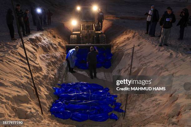 The shrouded bodies of Palestinians killed in nothern Gaza, that were taken and later released by Israel, are burried in a mass grave in Rafah, on...