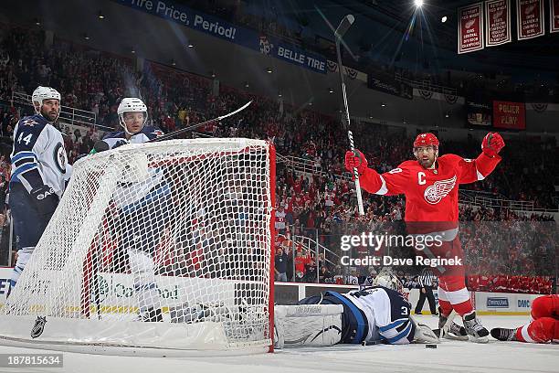 Henrik Zetterberg of the Detroit Red Wings raises his hands after teammate Pavel Datsyuk scores a goal while goalie Ondrej Pavelec of the Winnipeg...