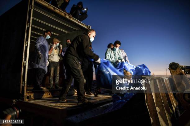 The bodies in body bags are being unloaded from a truck to be buried at Tel al-Sultan Cemetery in Rafah, Gaza on December 26, 2023. A mass funeral...