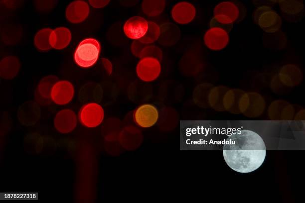 Full moon is seen among colorful light decorations placed on the streets in Turkish capital Ankara, Turkiye on December 26, 2023.