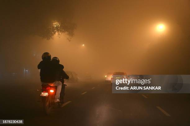 Motorists travel through dense fog on a cold winter morning in New Delhi on December 27, 2023.