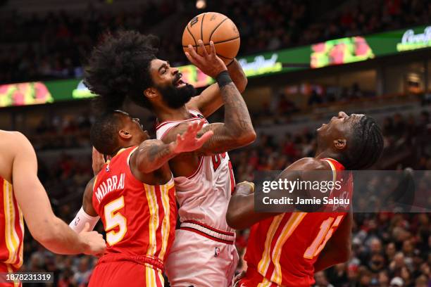 Coby White of the Chicago Bulls is fouled by Dejounte Murray of the Atlanta Hawks while also being defended by Clint Capela in the second half on...